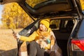 A beautiful positive woman in yellow clothes at a picnic sitting in the trunk of a car with her dog pomeranian takes a selfie Royalty Free Stock Photo