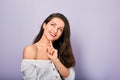 Beautiful positive young casual woman with hand under the face thinking and looking up in white shirt on purple background Royalty Free Stock Photo