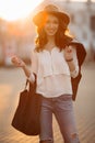 Brunette woman in hat walking at sunset after shopping.