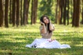 beautiful potrait asian woman siting and listening to headphone music in a pine forest and retro camera with rose flowers in frame