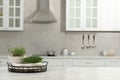 Beautiful potted microgreens on white table in kitchen, space for text