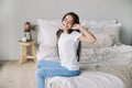 Beautiful pre-teen girl in casual clothes do stretching exercises seated on bed in cozy bedroom in the morning Royalty Free Stock Photo