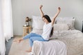 Beautiful pre-teen girl in casual clothes do stretching exercises seated on bed in cozy bedroom in the morning Royalty Free Stock Photo