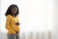 Beautiful pregnant african woman hugging her big belly at home Royalty Free Stock Photo