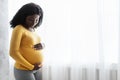 Beautiful pregnant african woman hugging her tummy at home Royalty Free Stock Photo