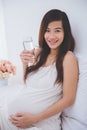 Beautiful pregnant asian woman holding a glass of water, smiling Royalty Free Stock Photo