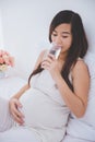 Beautiful pregnant asian woman holding a glass of water, smiling Royalty Free Stock Photo