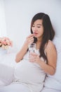 Beautiful pregnant asian woman holding a glass of water, taking Royalty Free Stock Photo