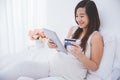 Beautiful pregnant asian woman holding tablet pc and credit card Royalty Free Stock Photo