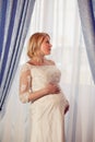 Beautiful pregnant bride posing against window