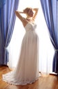 Beautiful pregnant bride posing against window