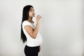 Beautiful pregnant brunette woman drinking water from the bottle on isolated white background Royalty Free Stock Photo