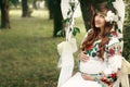 Beautiful pregnant brunette woman in embroidered white dress on Royalty Free Stock Photo