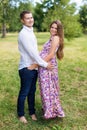 Beautiful pregnant couple happy together expecting a child. Man and woman walking in the park. Share the love and family, love con Royalty Free Stock Photo