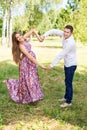 Beautiful pregnant couple happy together expecting a child. Man and woman walking in the park showing heart with hands. Share the Royalty Free Stock Photo