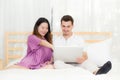 Beautiful pregnant family with laptop computer on bedroom