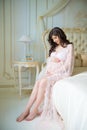 Beautiful pregnant girl in a lace negligee sitting on a bed of roses Royalty Free Stock Photo