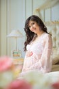 Beautiful pregnant girl in a lace negligee sitting on a bed of roses Royalty Free Stock Photo
