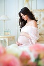 Beautiful pregnant girl in a lace negligee sitting on a bed Royalty Free Stock Photo