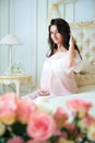 Beautiful pregnant girl in a lace negligee sitting on a bed Royalty Free Stock Photo