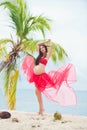 Beautiful pregnant girl in red dress on sandy beach with palm trees Royalty Free Stock Photo