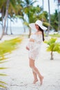 Beautiful pregnant girl in white dress and wide-brimmed hat on beach near palm trees Royalty Free Stock Photo