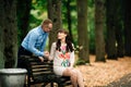 Beautiful pregnant stylish couple relaxing outside in the autumn park sitting on bench.