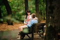 Beautiful pregnant stylish couple relaxing outside in the autumn park sitting on bench. Royalty Free Stock Photo