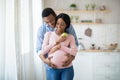 Beautiful pregnant woman with apple and her boyfriend hugging indoors Royalty Free Stock Photo