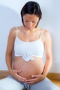 Beautiful pregnant woman with baby shoes on belly Royalty Free Stock Photo