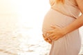 A beautiful pregnant woman on the beach touching her belly Royalty Free Stock Photo