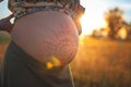 A beautiful pregnant woman on the beach touching her mehandi ornament belly with love and care at sunset lights Royalty Free Stock Photo