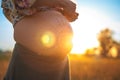 A beautiful pregnant woman on the beach touching her mehandi ornament belly with love and care at sunset lights Royalty Free Stock Photo