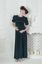 Beautiful pregnant woman in a black dress on a background of the fireplace with candles in white room Royalty Free Stock Photo