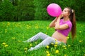 Beautiful pregnant woman blowing balloon