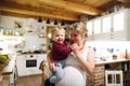 Beautiful pregnant woman carrying a toddler boy in the kitchen at home. Royalty Free Stock Photo