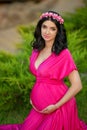 Beautiful pregnant woman with chaplet of flowers wearing in pink Royalty Free Stock Photo