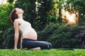 Beautiful pregnant woman doing prenatal yoga on nature outdoors.