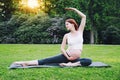 Beautiful pregnant woman doing prenatal yoga on nature outdoors.