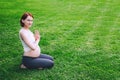 Beautiful pregnant woman doing prenatal yoga on nature outdoors. Royalty Free Stock Photo