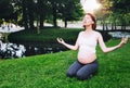 Beautiful pregnant woman doing prenatal yoga on nature outdoors. Royalty Free Stock Photo