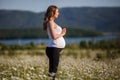 Beautiful pregnant woman doing sports in the camomile field Royalty Free Stock Photo