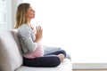 Beautiful pregnant woman doing yoga, sitting in lotus position at home. Royalty Free Stock Photo