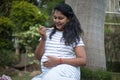 Beautiful pregnant woman eating snacks or junk food in park, enjoying meal. Royalty Free Stock Photo