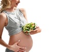 Beautiful pregnant woman hold organic salad and fork with tomato. Pregnancy motherhood expectation healthy eating Royalty Free Stock Photo