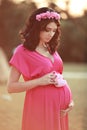 Beautiful pregnant woman holding baby's bootee over nature park