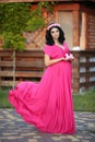 Beautiful pregnant woman holding baby's bootee wearing in pink d Royalty Free Stock Photo