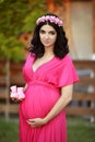 Beautiful pregnant woman holding baby's bootee wearing in pink d Royalty Free Stock Photo