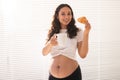 Beautiful pregnant woman holding croissant and cup of coffee in her hands during morning breakfast. Concept of good Royalty Free Stock Photo