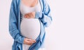 Beautiful pregnant woman hugging her belly in white background. Expectant mother waiting for baby birth during pregnancy. Concept